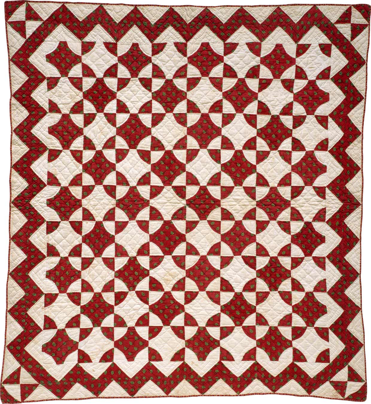 A quilt with a highly-regular geometirc red and white pattern.